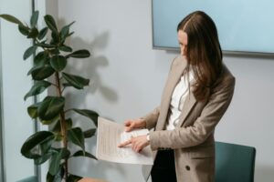 Professional woman in a brown blazer reviewing a document in an office setting.