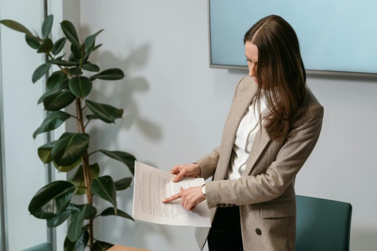 Professional woman in a brown blazer reviewing a document in an office setting.